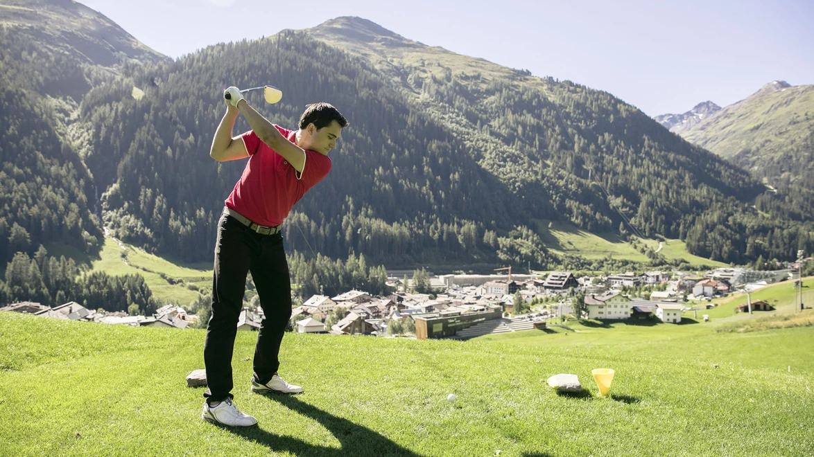 Golfer beim Abschlag am Golf-Club Arlberg mit Blick auf St. Anton am Arlberg